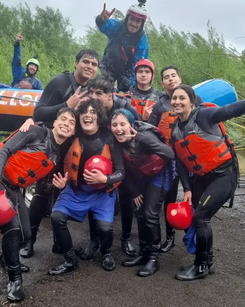 Grupo con trajes de agua, chalecos y cascos celebrando después del rafting con PR Tours